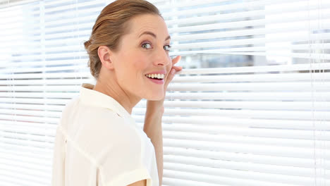 Happy-businesswoman-peeking-through-the-blinds