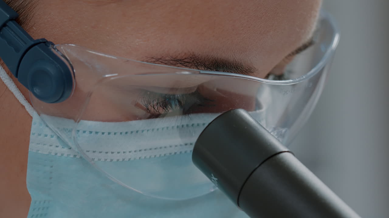 Chemist looking through microscopic lens on optical tool