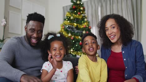 smiling african american family having video call and gesturing, christmas decorations in background