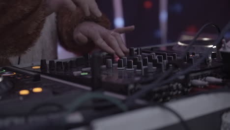 close up of hands of a dj dressed in a fluffy costume playing and scratching the decks and mixing music in slowmotion log