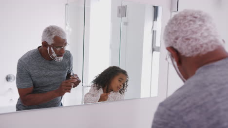 Abuelo-En-Pijama-En-El-Baño-Afeitándose-Mientras-Su-Nieta-Mira