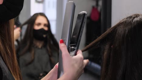 professional hairdresser uses a curling iron while doing a hairstyle