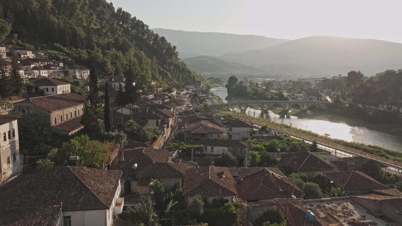 Berat Albania Aerea v11, sorvolo a bassa quota del quartiere Gorica che cattura il ponte sul fiume Osum, il paesaggio urbano in stile ottomano e la montagna collinare al tramonto. Girato con Mavic 3 Pro Cine - 11 luglio 2024.