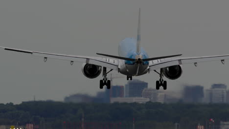 airplane landing on runway with city skyline in background