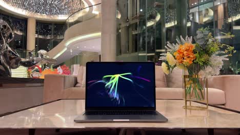 laptop on a marble table displaying screensaver inside luxurious mansion home