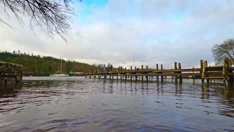 lake windermere in the english lake district, with its iconic wooden jetty, historic stone-built buildings, and moody grey skies