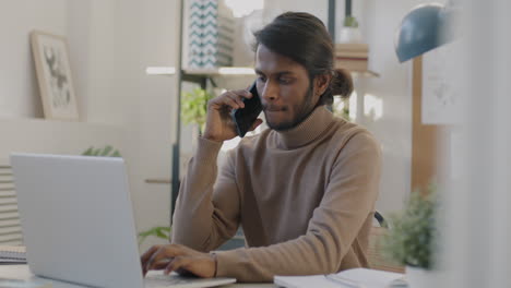 hombre trabajando en la computadora portátil y hablando por teléfono