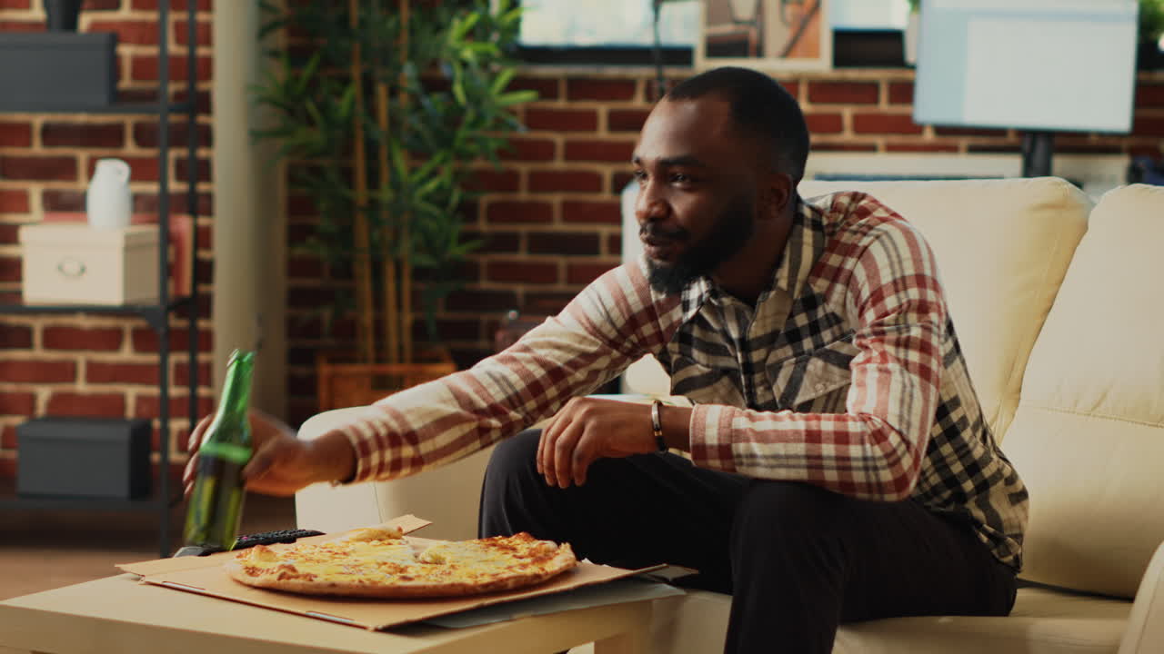 African american guy eating slices of pizza from takeout