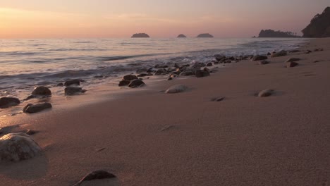 beach shot at dusk with warm light , islands in distance and small waves lap the shore