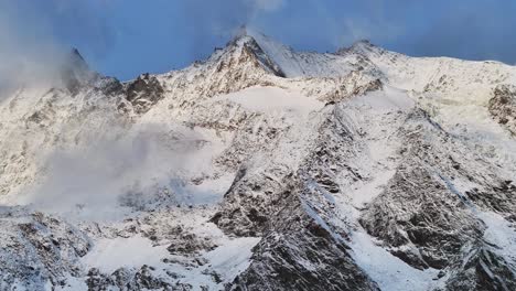 mount dom ulrichschorn gumshoe stalden saas fee ski resort saastal swiss alps valley switzerland drone aerial morning sunrise snow mountain peaks low clouds fog layer slow pan left motion