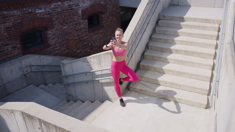 a beautiful young blonde girl makes a selfie after an outdoor workout on the concrete stairs