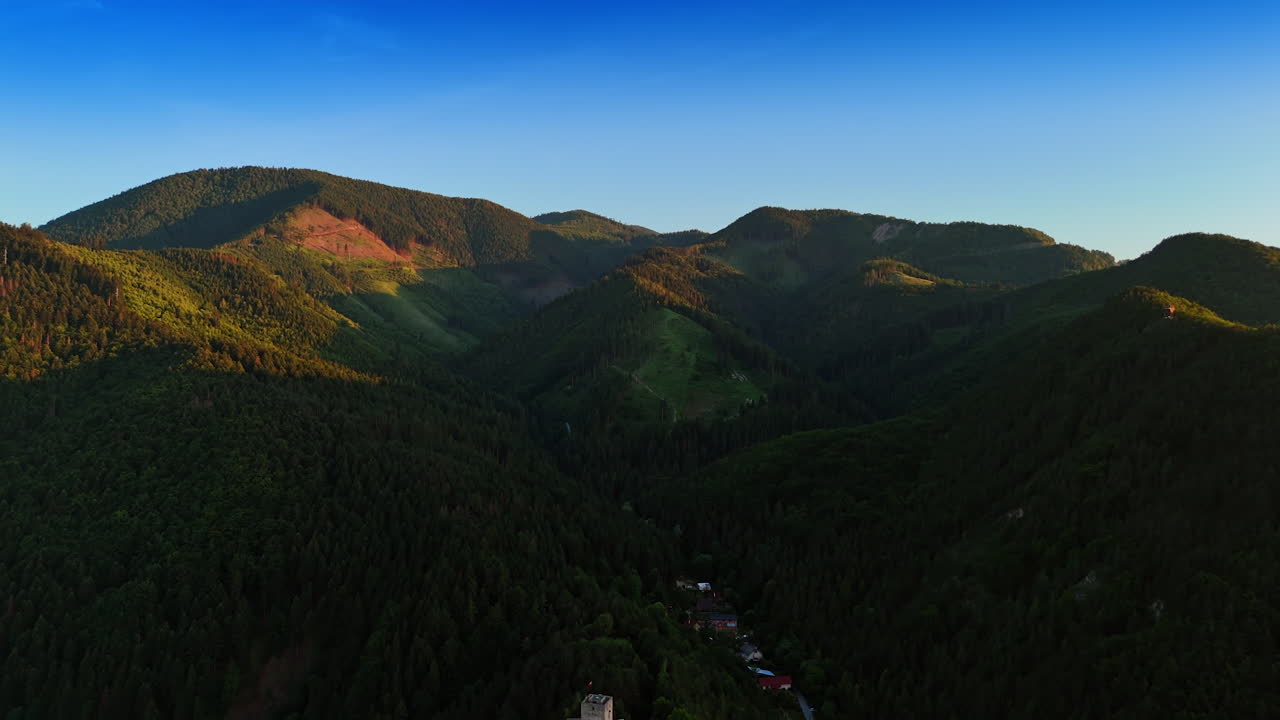 Castle view in mountain landscape. Aerial view of a stunning mountain landscape with a historic castle amid lush greenery in daylight