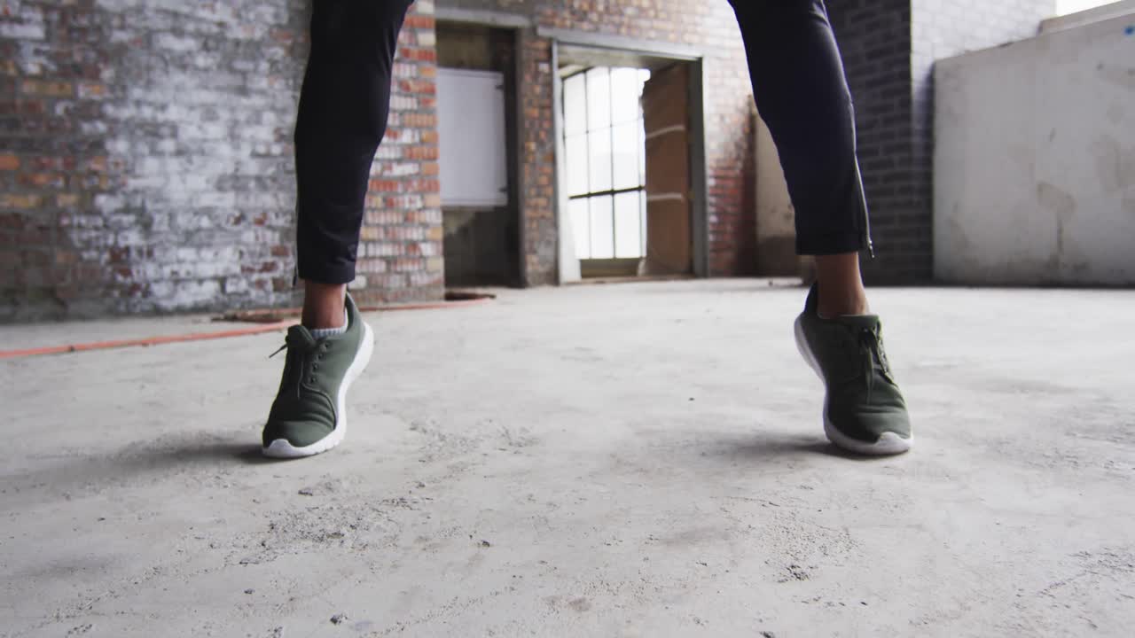 hombre afroamericano haciendo ejercicio con una pelota de medicina en un edificio urbano vacío