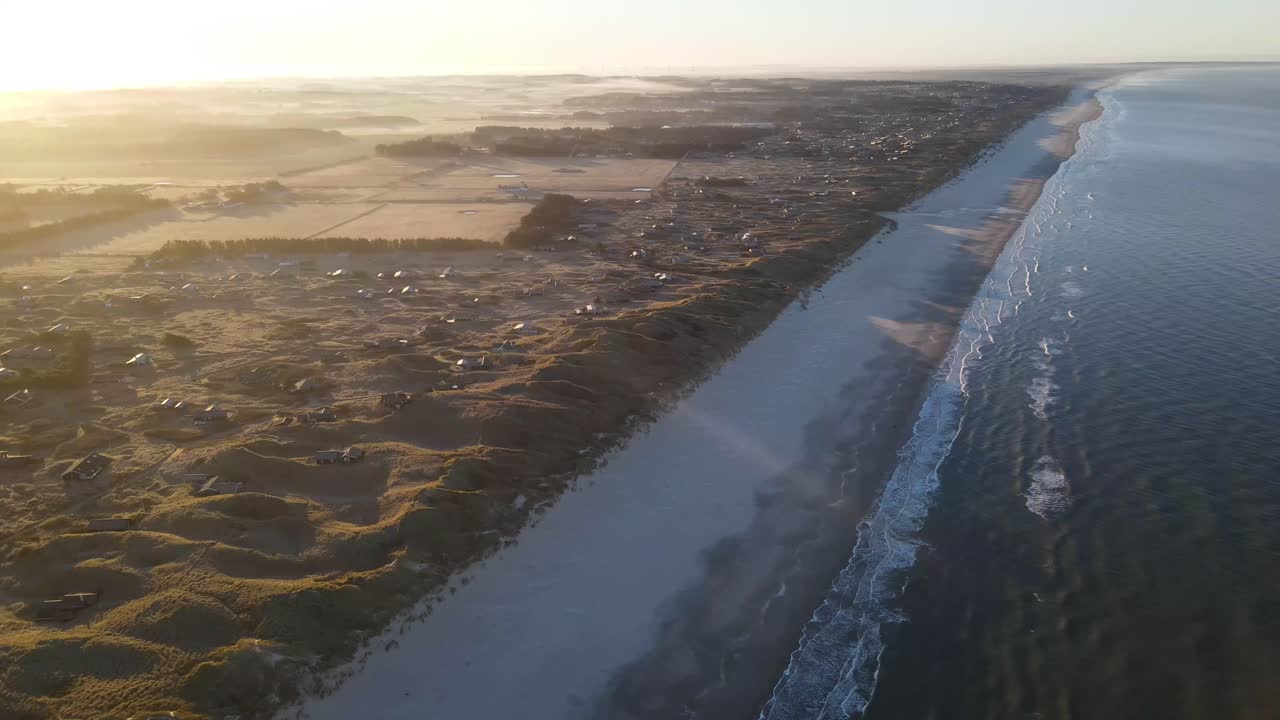 vista aérea de las olas y el amanecer en el océano cerca de løkken junto al mar del norte, dinamarca
