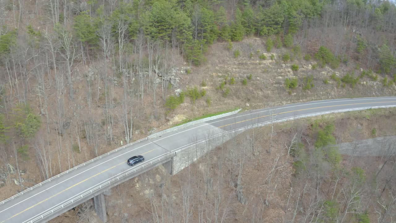 Aerial View of a Car Driving on a Winding Mountain Road