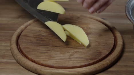 a chef cuts raw potatoes into small slices