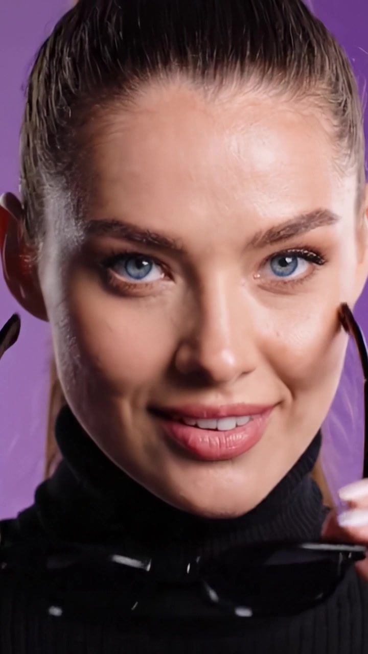 Modella elegante che sfoggia occhiali da sole alla moda con un sorriso fiducioso e un aspetto raffinato, ripresa su uno sfondo vivace per un video di moda.