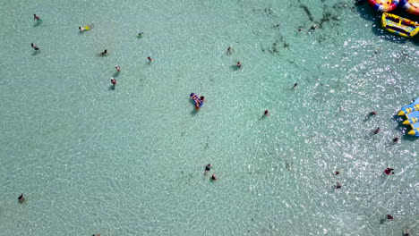 Aerial-overhead-footage-of-people-bathing-at-a-shallow-sandy-beach