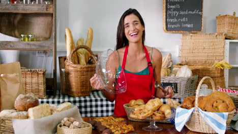 female staff arranging bread on counter at bakery store