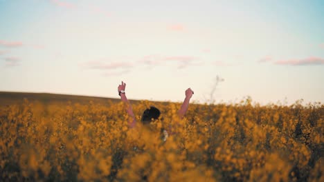 Peace-and-love-concept,-woman-coming-out-of-the-bush-at-sunset-and-making-the-symbol-of-victory-with-her-hands-at-sunrise