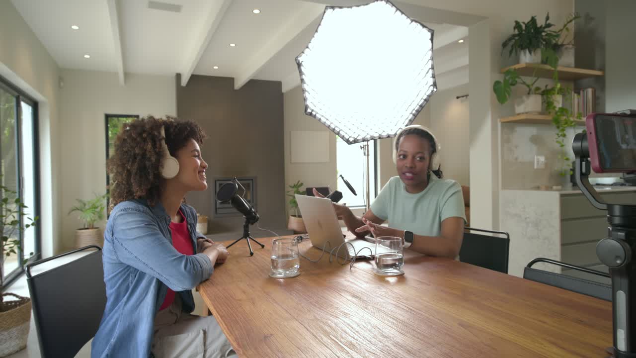 Diverse conduttrici che prendono le cuffie, rispondono al telefono e al microfono, iniziando un podcast al tavolo della cucina