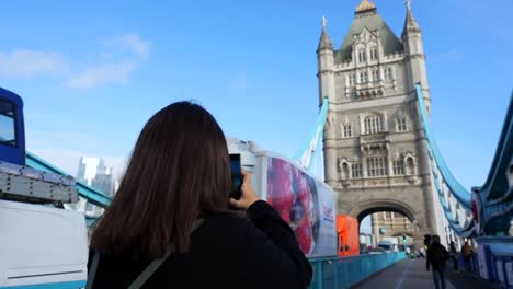 tourist captures the iconic tower bridge on a clear day in london with vehicles and pedestrians around