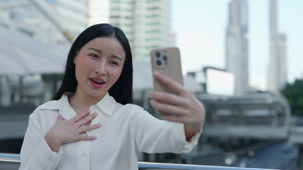 Young Asian Woman Takes a Selfie or Makes a Video Call in the City