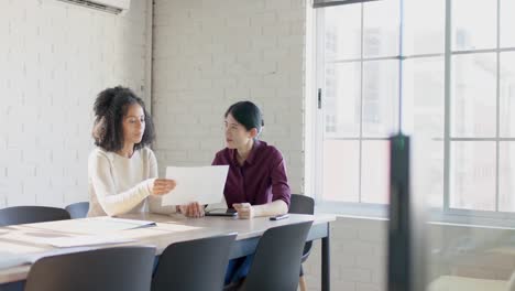 busy diverse casual businesswomen at table discussing project in office in slow motion