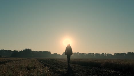 un hombre camina a través de un campo quemado al amanecer y al atardecer. silueta