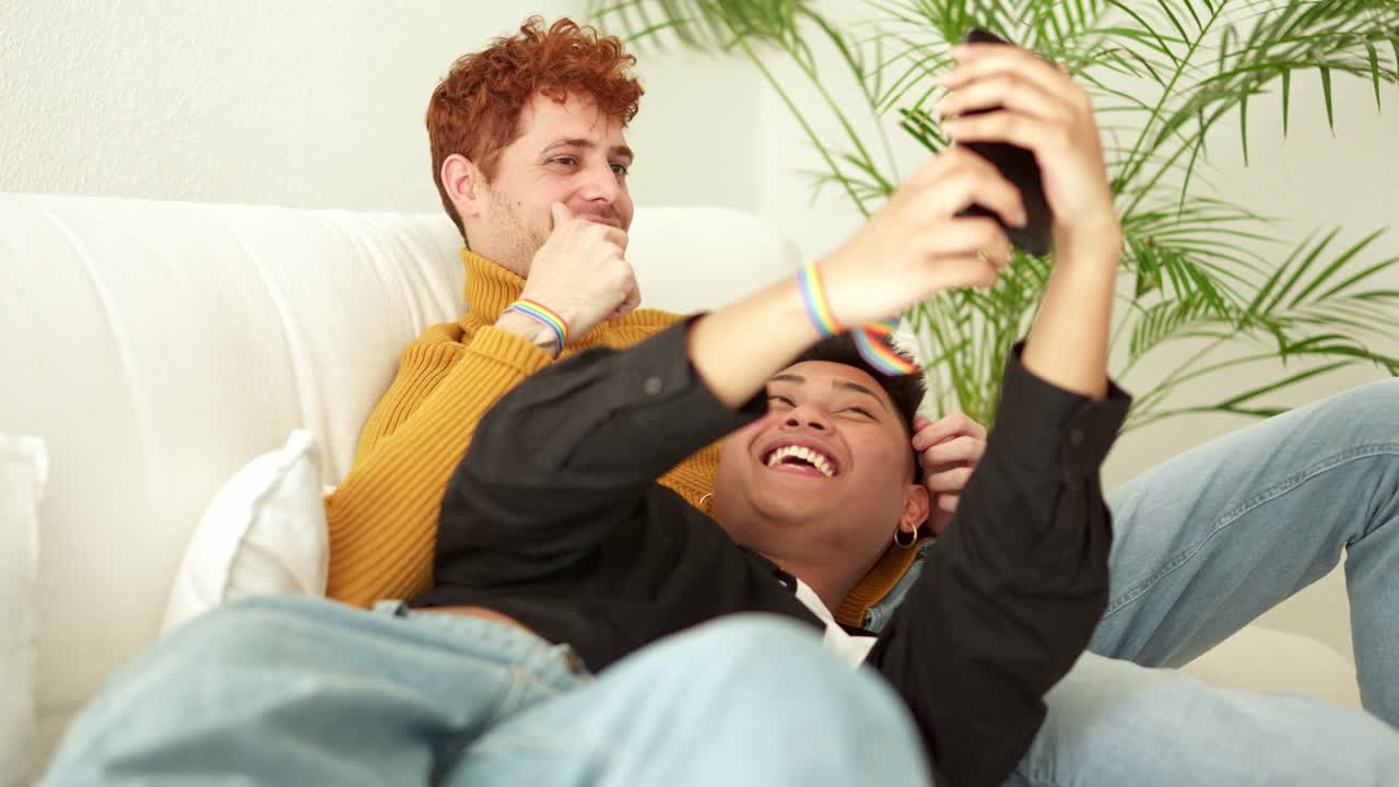Happy Gay Couple Taking a Selfie on the Couch at Home