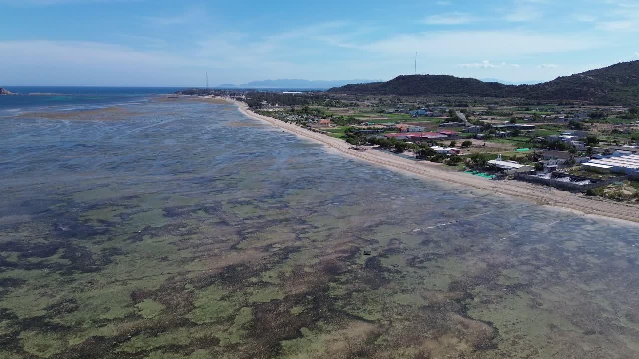 Tilting up aerial shot revealing the expansive My Hoa Lagoon and its shallow coastal waters in Phan Rang, Vietnam.