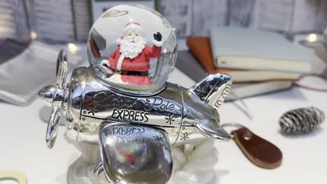 figurina de santa claus volando un avión de aspecto vintage en una ventana con luces de navidad