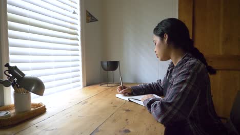 concentrated young caribbean female writing notes and feelings in her personal journal