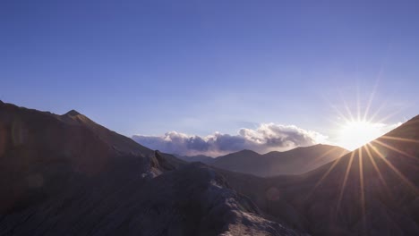 sun setting over a volcano creator, rocky landscape with low fluffy cloud formation and copyspace above