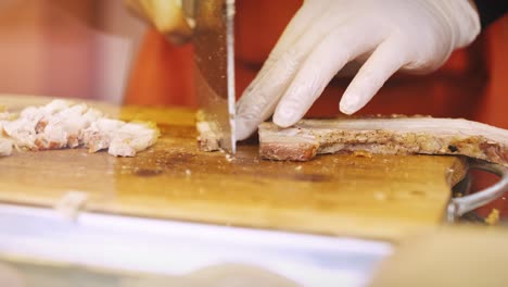 Handheld-view-of-man’s-hand-cutting-meat