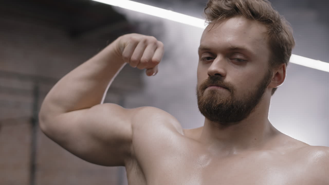 Portrait of Muscular Caucasian Sportsman Showing Biceps