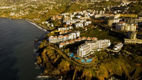 hyperlapse-of-a-block-of-hotels-in-a-prime-spot-on-the-madeiran-coast-line,-showing-the-waves-crashing-all-down-the-coast-with-an-anti-clockwise-direction