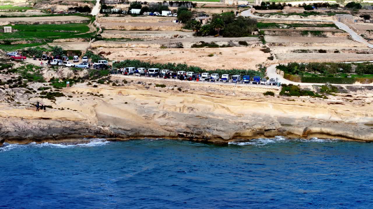 Panoramica aerea scenica di aspre scogliere calcaree e acque cristalline turchesi nella Blue Lagoon tra le isole di Comino e Gozo a Malta durante una giornata estiva luminosa e soleggiata, con un'ampia angolazione