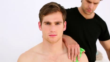 physiotherapist applying kinesio tape to patients shoulder