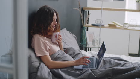 woman working on laptop in bed