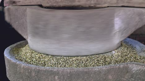 close up of a woman using hand-turned millstone to grind green bean