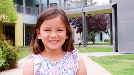 Una-Colegiala-De-Primaria-Sonriendo-A-La-Cámara-En-El-Patio-De-La-Escuela