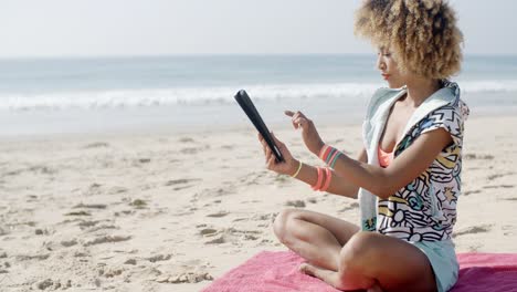mujer usa tableta táctil en la playa