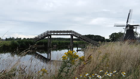 Schöne-Aufnahme-Einer-Kleinen-Windmühle-In-Der-Nähe-Einer-Schönen-Brücke-In-Einem-Kleinen-Bach