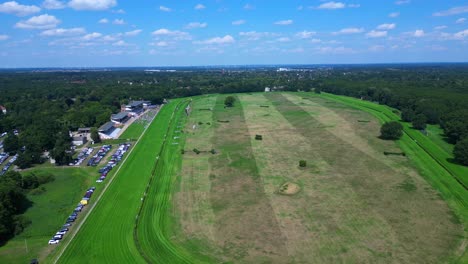 horse racing track with spectators enjoying the competition on a sunny summer day. perfect aerial view flight fly push forward drone