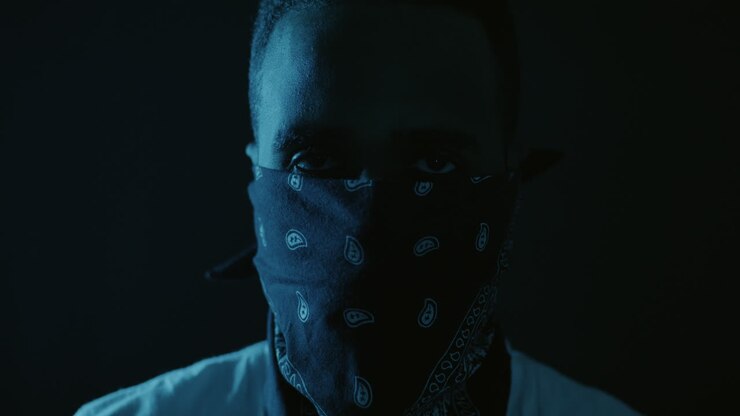 Uomo che indossa una maschera a bandana sotto una luce blu.