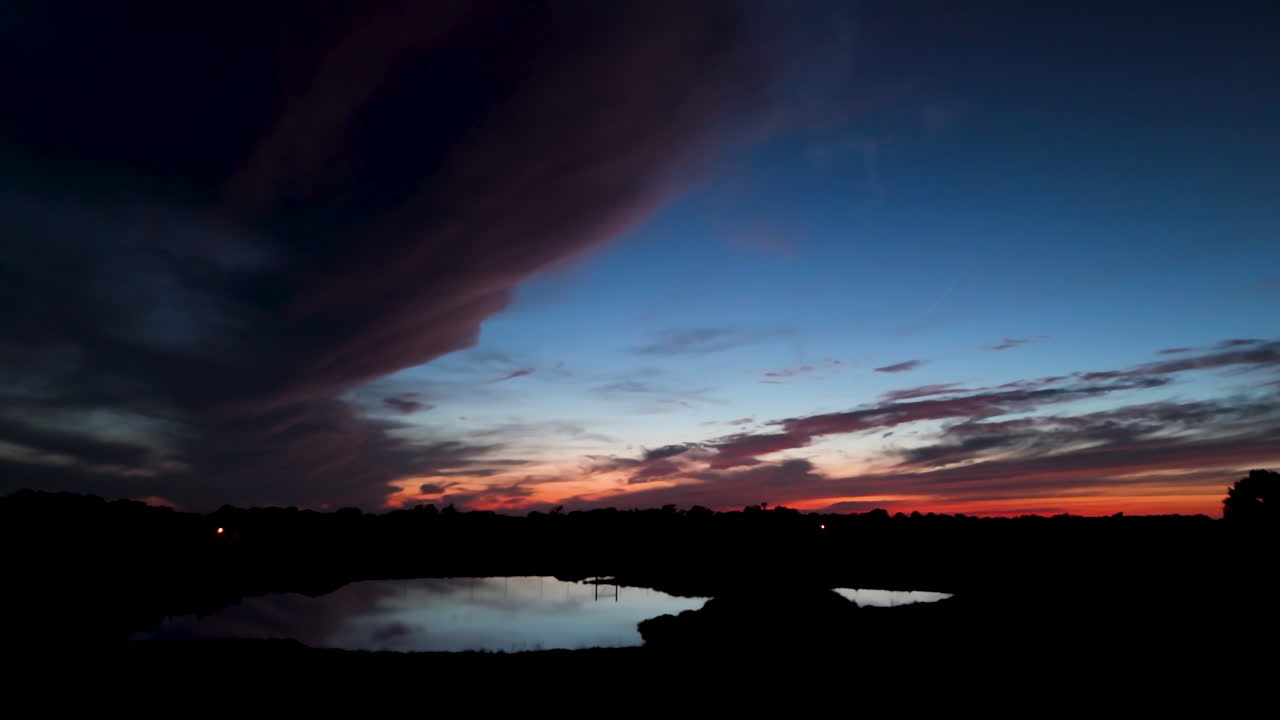 Evening sunset in nature with reflection on water. Dark blue sky and silhouetted landscape