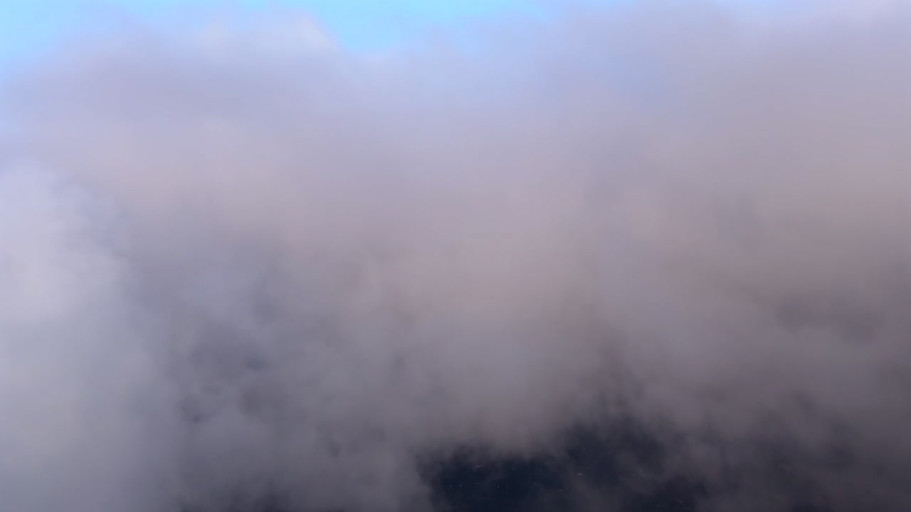 An immersive pilot’s view flying through and into a layer of ethereal clouds bathed by the sunset light under a soft pastel color sky, as seen from a jet cockpit