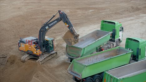 dump truck positioning for excavator to load dirt on active construction site for earthmoving and site preparation. preparatory work done on a construction site before the actual building.