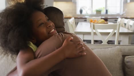 african american daughter and her father smiling and hugging on couch